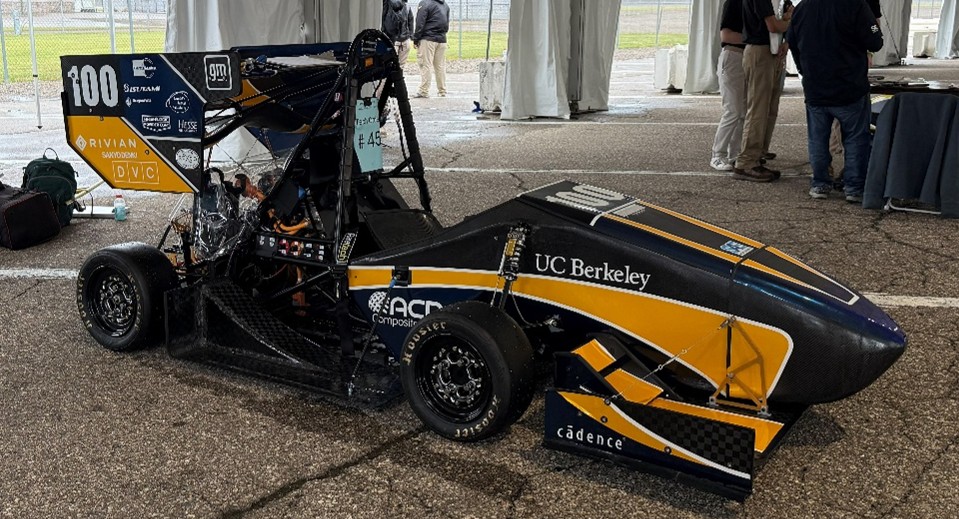 Racing dragster with UC Berkeley colors and sponsor decals parked under a tent.